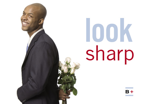 a smiling black man in a suit holding a bunch of white roses behind his back, captioned 'look sharp'