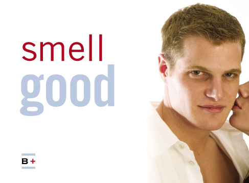 a white man in a white shirt looks at the camera as a woman's lips enter the frame to kiss him, captioned 'smell good'